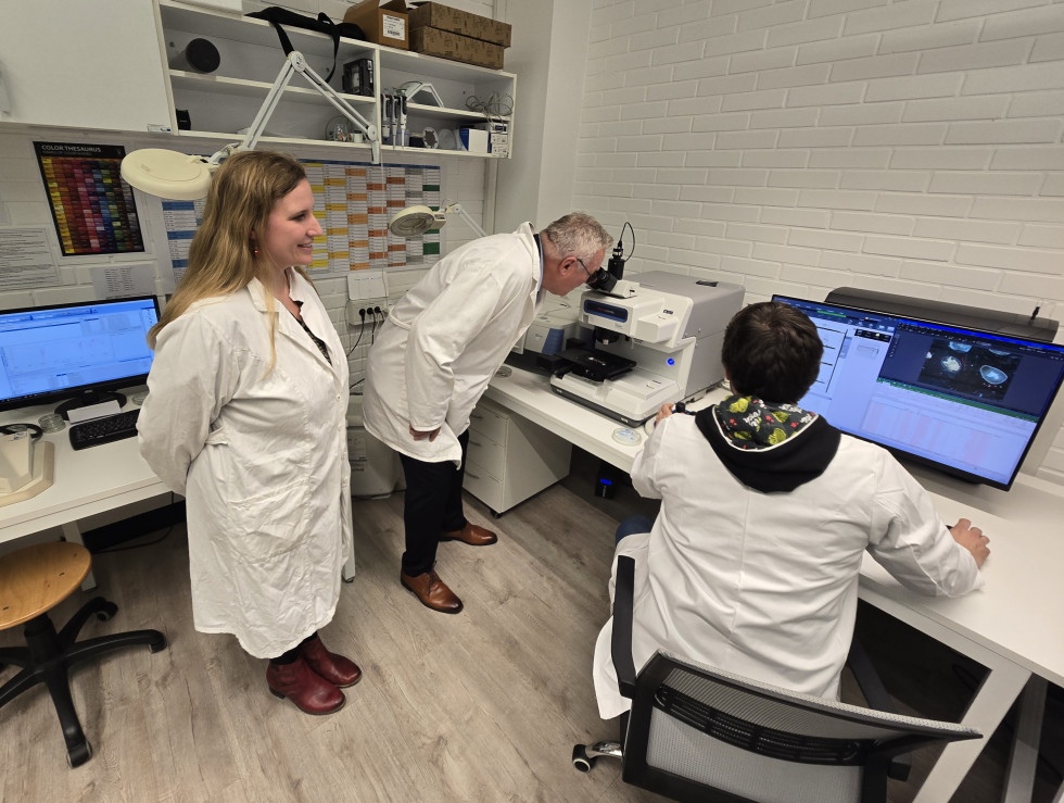 Minister Novak v laboratoriju ob ogledu mikroskopa za analizo onesnaženosti vode, levo in desno sta sodelavca inštituta