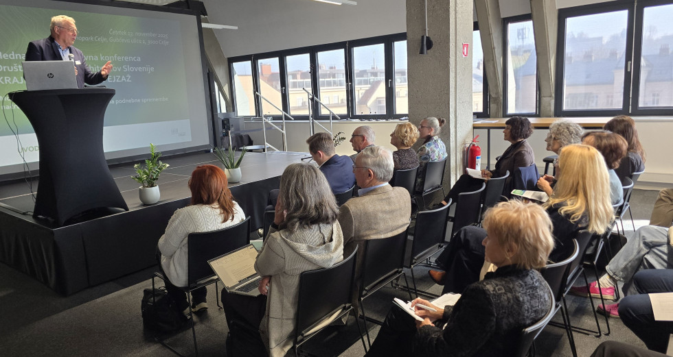 Minister Novak predava za govornico v dvorani poslušalcem v publiki.