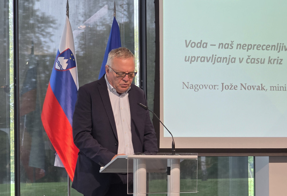 Minister na odru nagovarja zbrane poslušalce na konferenci 