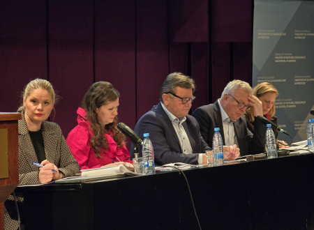 Vladni predstavniki sedijo na govorniškem odru, med njimi ministra Novak in Jevšek