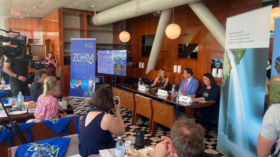 govorci sedijo za mizo in nagovarjajo zbrane na tiskovni konferenci