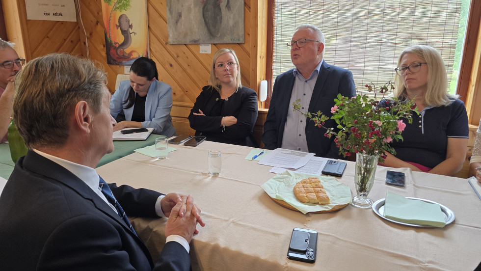 Minister sedi za omizjem in se pogovarja z zbranimi