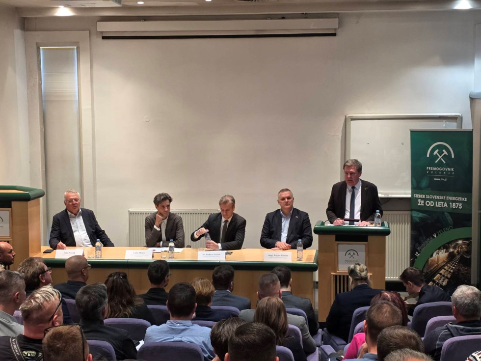 V sejni sobi v ospredju poslušalci, v ozadju predsednik vlade in ministri, ki predstavljajo novosti glede zapiranja premogovnika Velenje