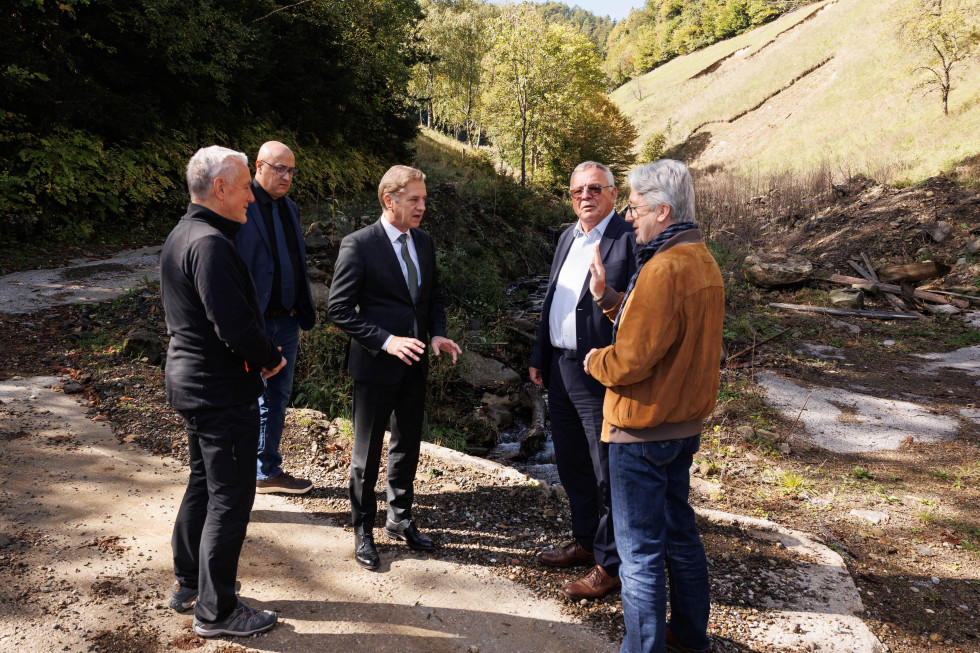 Predsednik vlade Golob, minister Novak in državni sekratr Šefic si ob hudourniku ogledujejo protipoplavne ukrepe