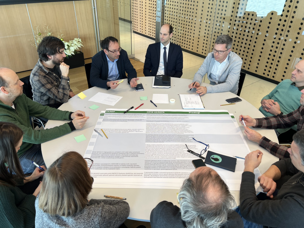 Udeleženci delavnic sedijo za skupno okroglo mizo in razpravljajo.