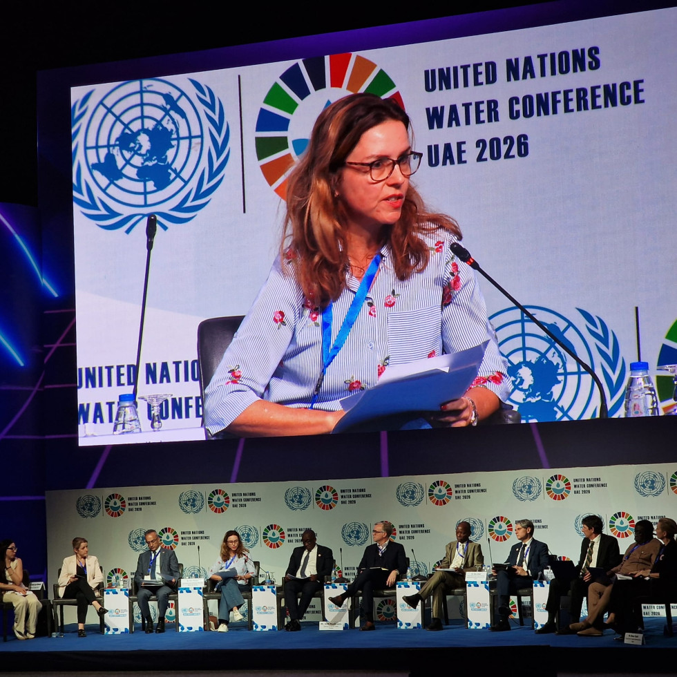 Državna sekretarka v Kabinetu predsednika vlade sedi za omizjem strokovnega srečanja in nagovarja zbrane