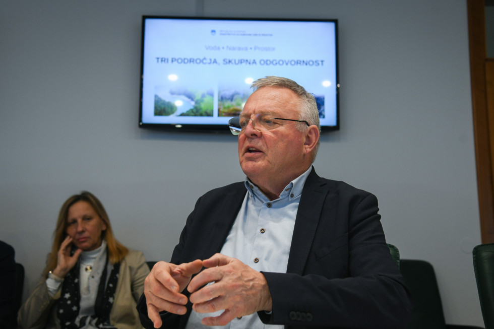 Minister Novak v sejni sobi pred projekcijo predstavlja gradivo