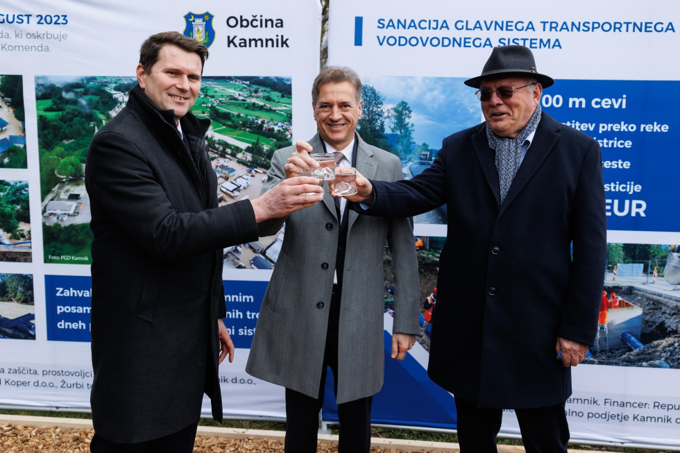 Župan Slapar, predsednik vlade Golob in minister Novak na odprtju prenovljenega vodovoda, v rokah držijo kozarce