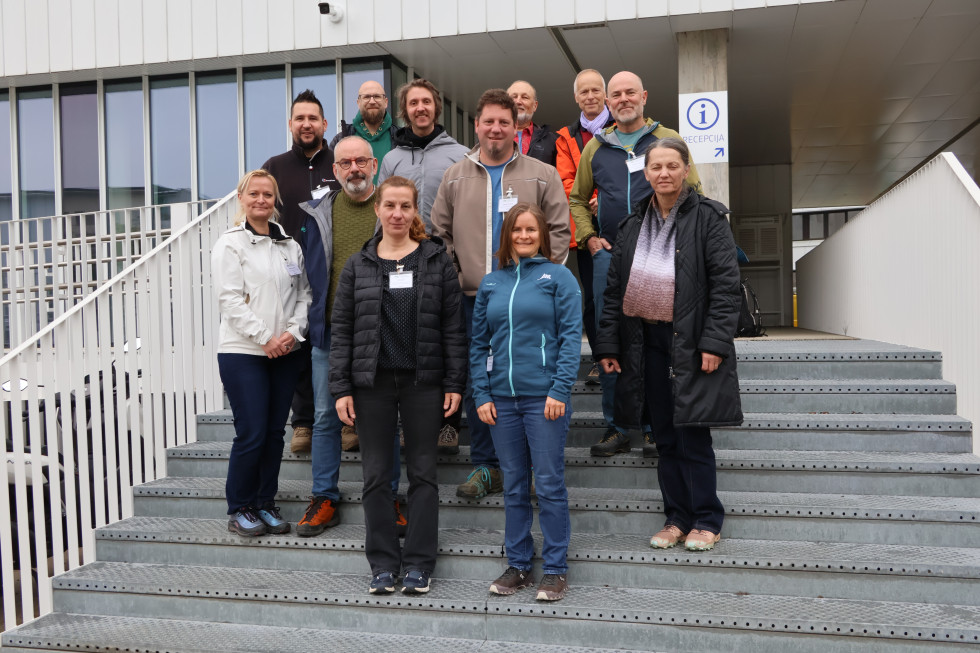 Moški in ženske stojijo eden zraven drugega na stopnicah pred zgradbo.