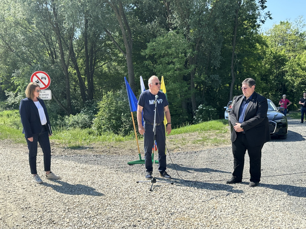 Trije sogovorniki stojijo in nagovarjajo zbrane