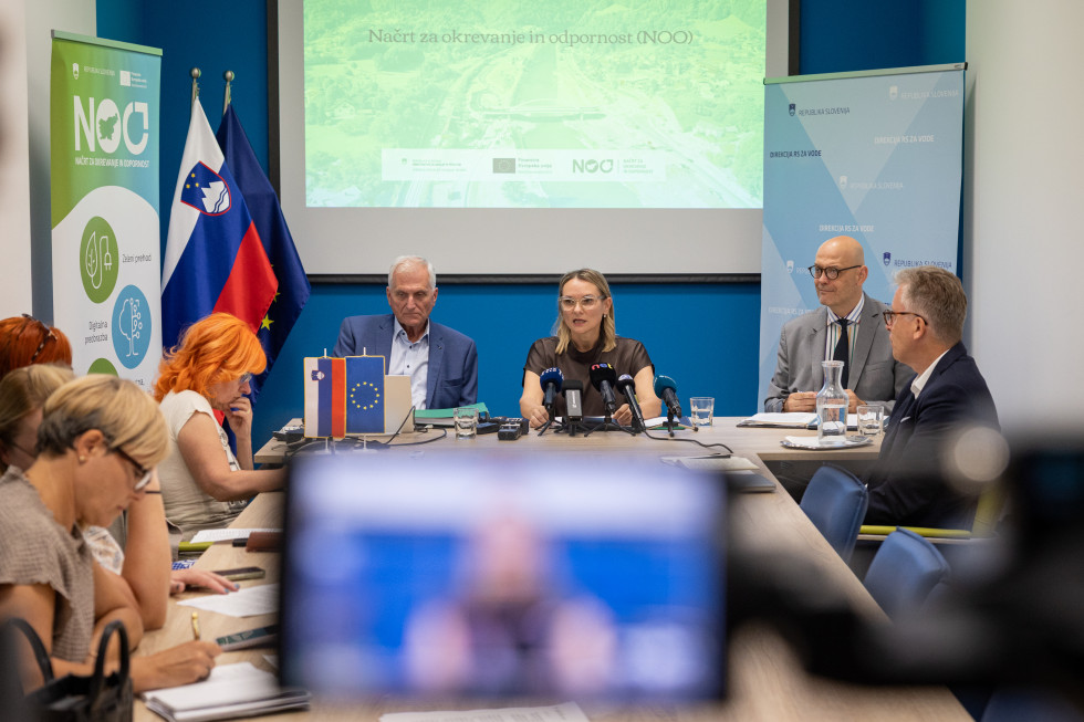 V ospredju mikrofoni in kamere, v ozadju nastopajoči na novinarski konferenci