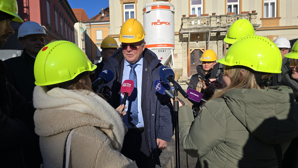 Minister stoji na gradbišču in odgovarja novinarjem