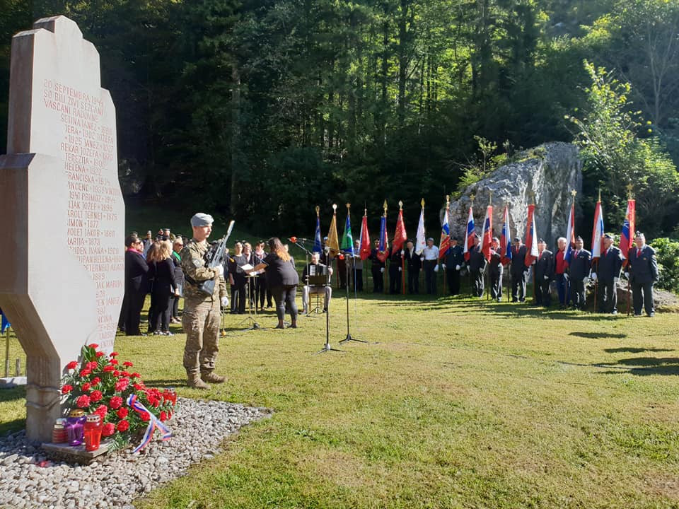 Udeleženci dogodka stojijo ob spomeniku Roka