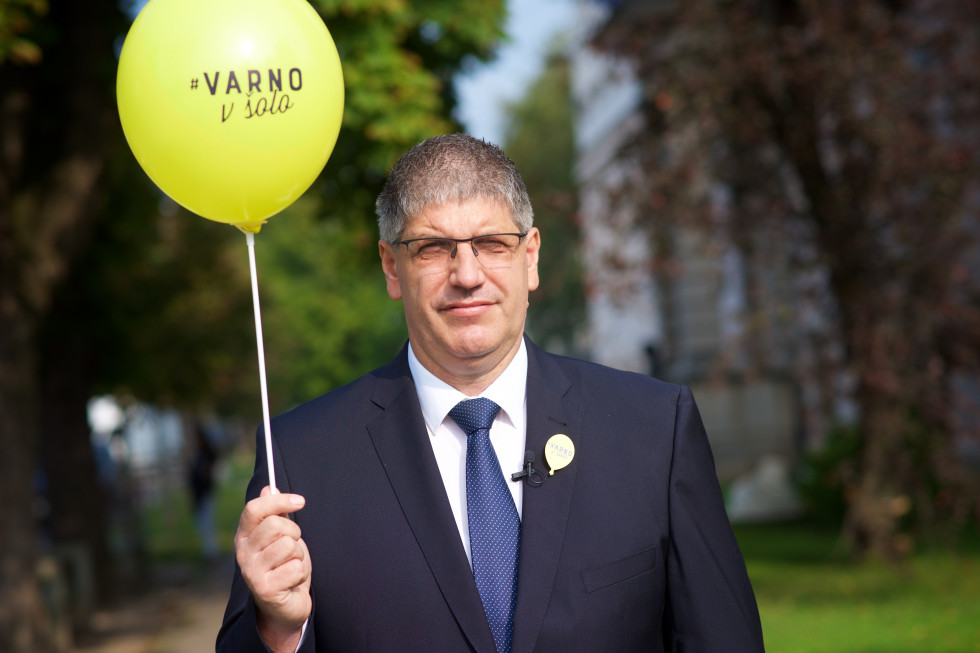 Minister za notranje zadeve Boštjan Poklukar z rumenim balonom v roki. Na balonu piše Varno v šolo.