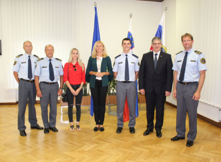 Generalna direktorica policije mag. Tatjana Bobnar, Tim Gajser v policijski uniformi in notranji minister Boštjan Poklukar ter policisti stojijo pred zastavami.