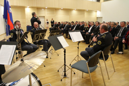 Člani Policijskega orkestra med igranjem v ospredju, v ozadju sedijo udeleženci dogodka