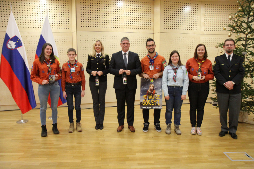 Na odru stojijo minister Boštjan Poklukar, generalna direktorica policije Tatjana Bobnar, vikar Igor Jereb in pet skavtov in skavtinj