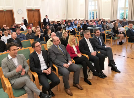 Udeleženci konference sedijo in poslušajo