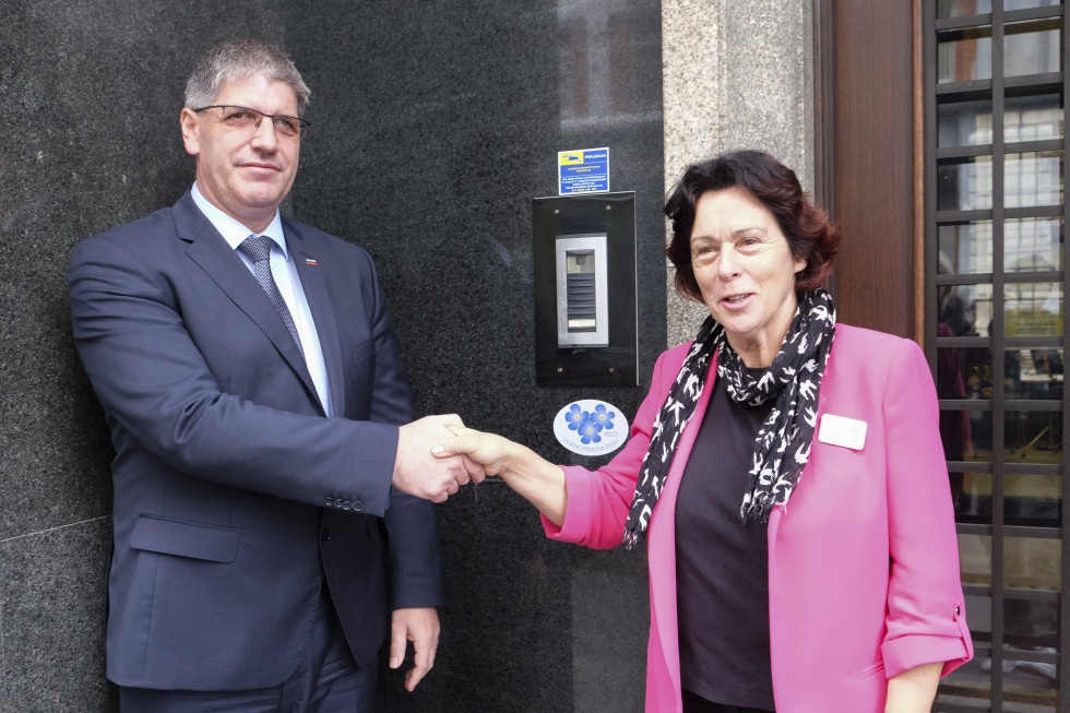 Minister Boštjan Poklukar in predsednica združenja Spominčica - Alzheimer Slovenija Štefanija Lukič Zlobec se rokujeta pred vhodom na ministrstvo na Štefanovi 5