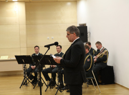 Minister Boštjan Poklukar za govornico, v ozadju člani policijskega orkestra