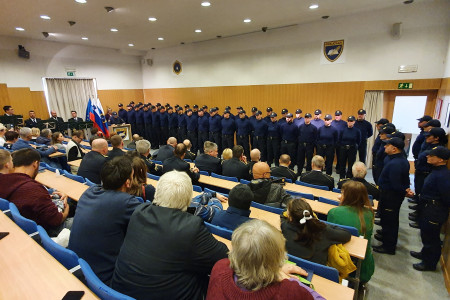 Dvorana z gosti v ospredju, zadaj policisti v dveh vrstah