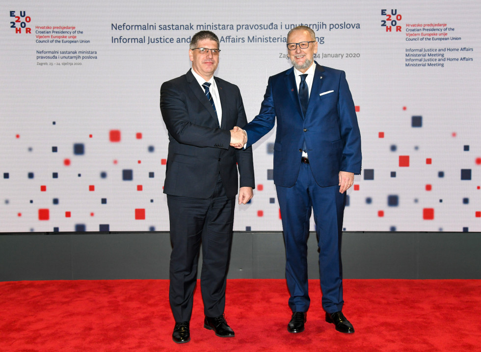 Ministra Poklukar in Božinović se rokujeta pred ozadjem hrvaškega predsedstva
