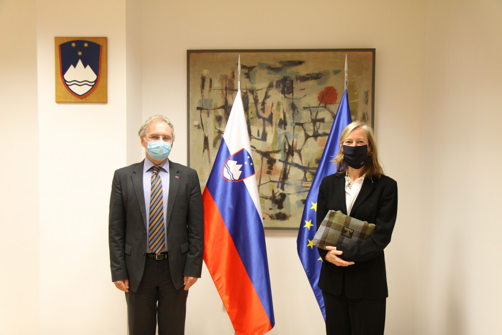 Minister Aleš Hojs in veleposlanica Tiffany Sadler stojita pred zastavami