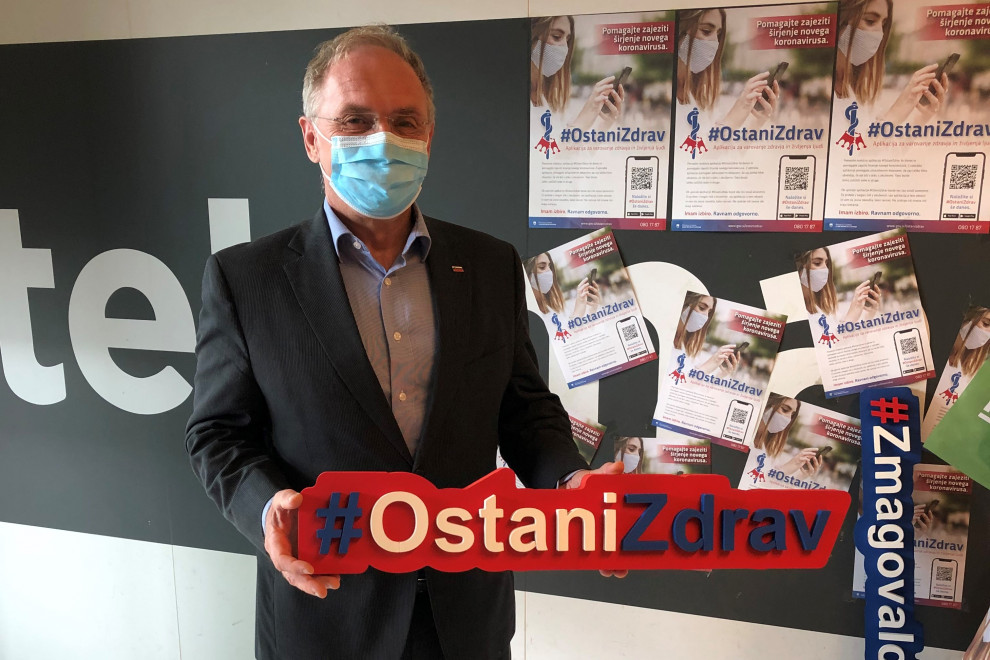 Minister Aleš Hojs drži napis Ostani zdrav.