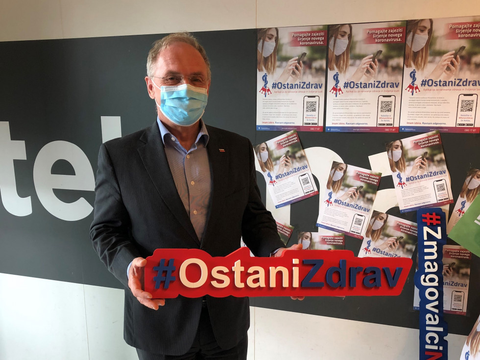 Minister Aleš Hojs drži napis Ostani zdrav.