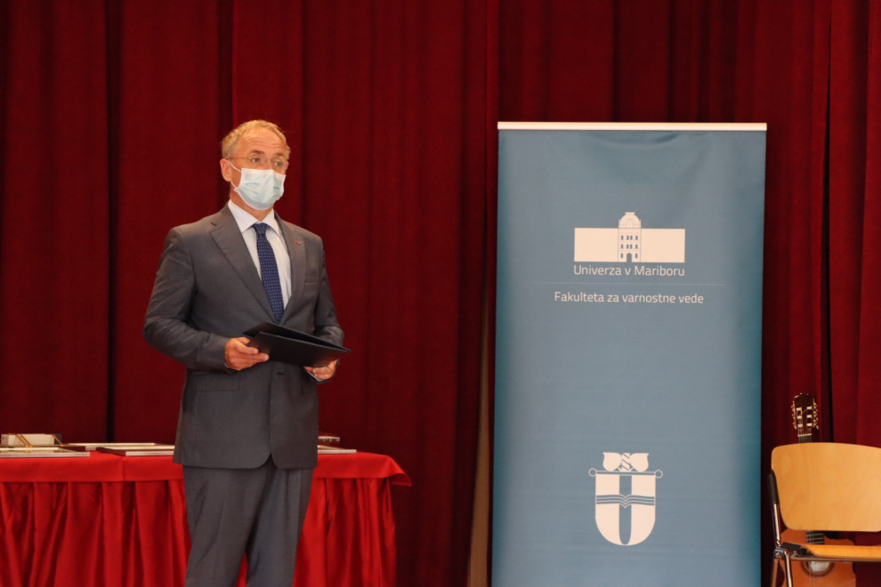Minister za notranje zadeve Aleš Hojs ob nagovoru na odru, poleg plakata z napisom Fakulteta za varnostne vede. Minister nosi masko.