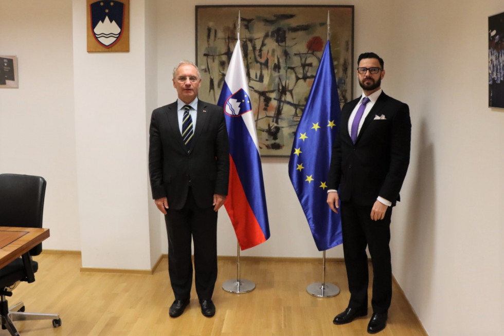 Minister za notranje zadeve Aleš Hojs in madžarski veleposlanik Andor Ferenc Dávid stojita pred zastavami.
