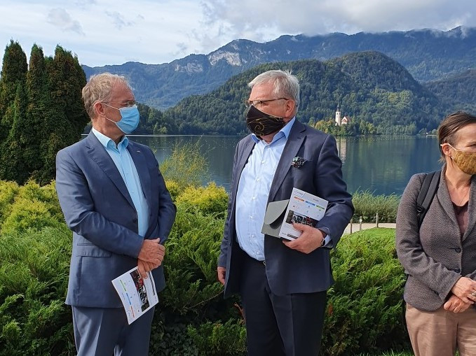 Minister Aleš Hojs v pogovoru z blejskim županom Janezom Fajfarjem, v ozadju jezero in blejski otok.