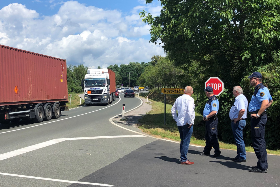 Kolona vozil na mejnem prehodu Novokračine, cesta polna tovornih in osebnih vozil, na desni državni sekretar in župan ter dva policista.