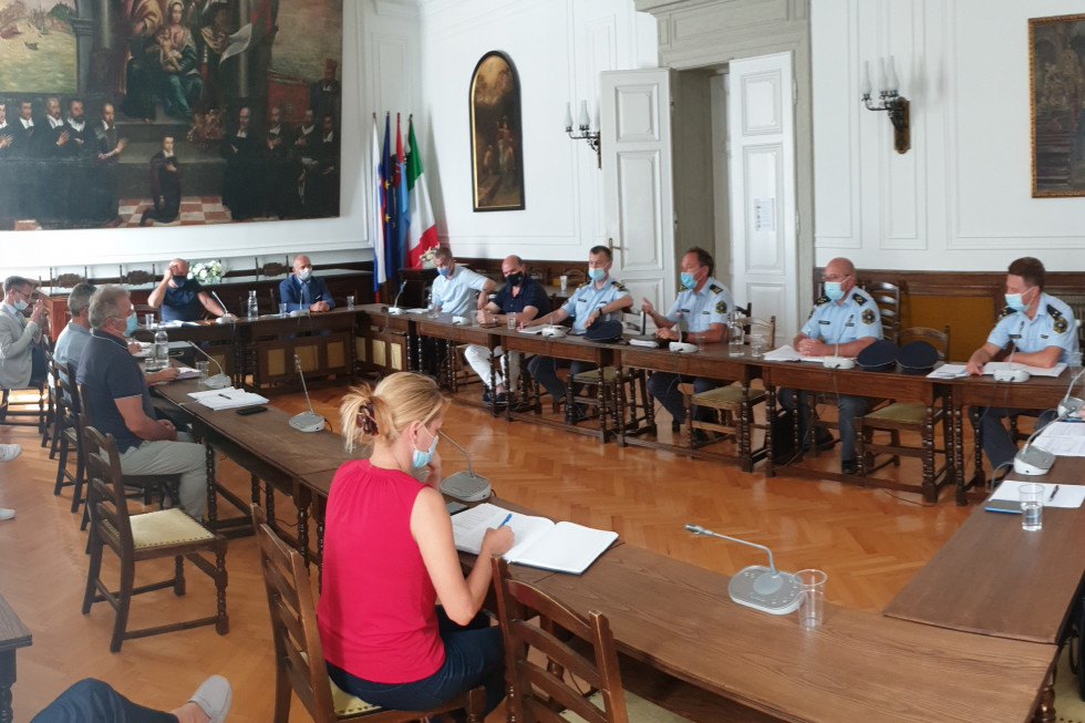 Udeleženci sestanka o varnostni in prometni problematiki v Občini Piran med predstavniki občine, ministrstva in policije, vsi sedijo za veliko rjavo ovalno sejno mizo.