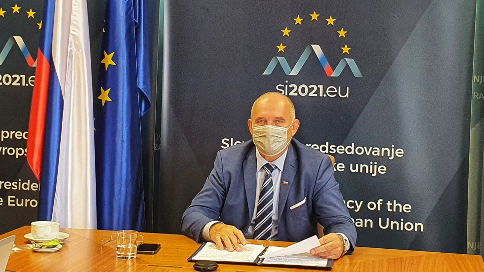Državni sekretar dr. Božo Predalič sedi za mizo, za njim ozadje z logotipom slovenskega predsedovanja Svetu Evropske unije