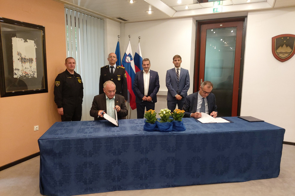 Minister za notranje zadeve Aleš Hojs in predstavnik podjetja Leonardo S.p.A., Italija,  Andrea Mirteto sedita za mizo, pred sabo imata mapo, v kateri je pogodba za nakup helikopterja