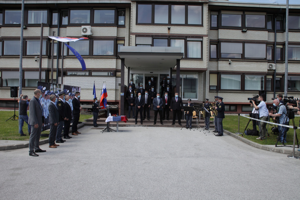 Udeleženci prireditve ob 30-letnici Centra za varovanja in zaščito stojijo pred zgradbo, kjer poteka prireditev
