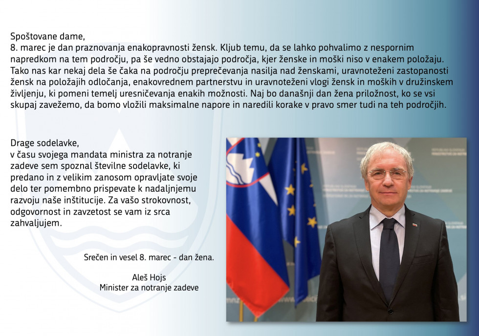 Minister Aleš Hojs stoji pred zastavami, v ozadju njegova poslanica ob dnevu žena