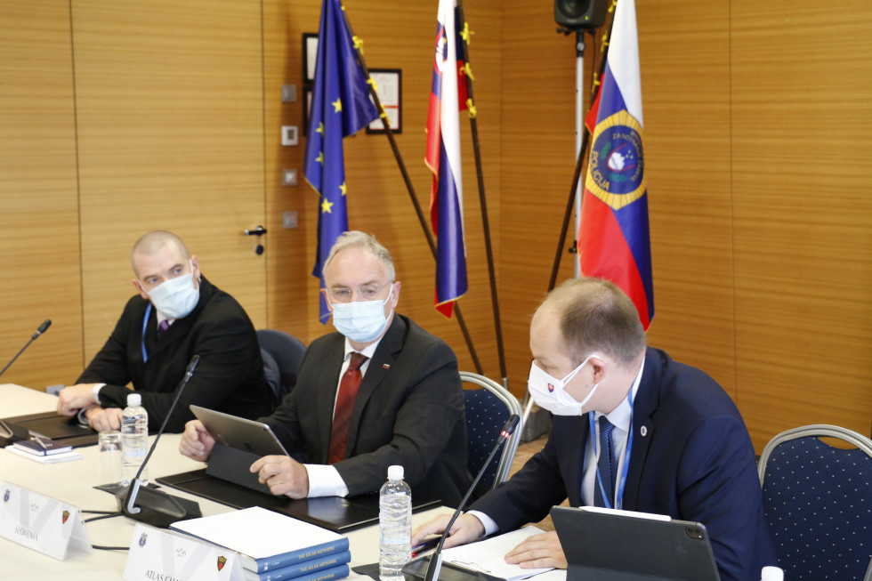 Official speakers sit at a table with microphones