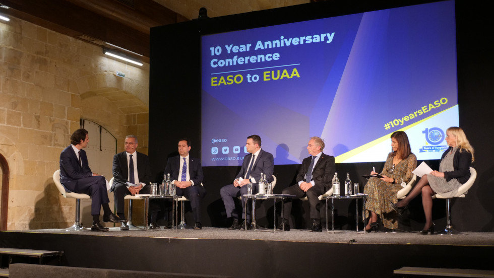 Official speakers sit in a semicircle on stage