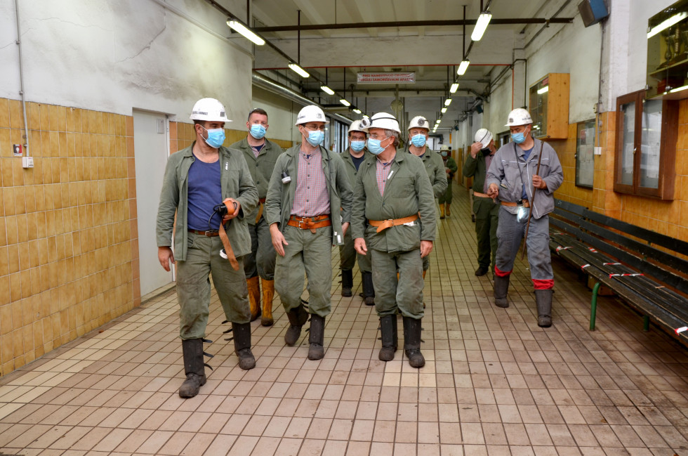 Minister Aleš Hojs si je ogledal delo rudarjev v premogovniku. Rudarji in minister hodijo po hodniku, oblečeni v rudarska oblačila.