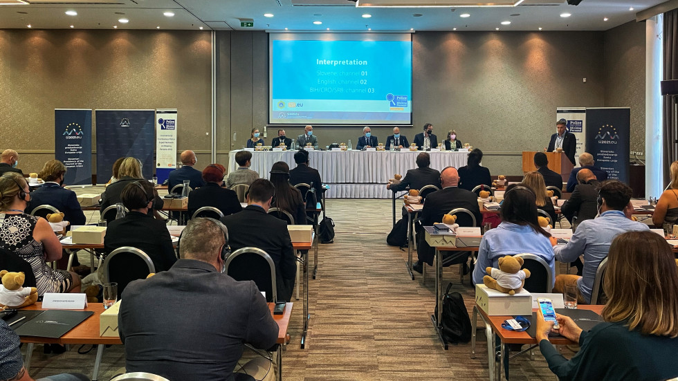 Participants in the hall with a view of the stage, the central screen and the speaker Damjan Miklič, The President of the Police Expert Network on Missing Persons and Head of the Homicide and Sexual Offences Section of the Slovenian Police.