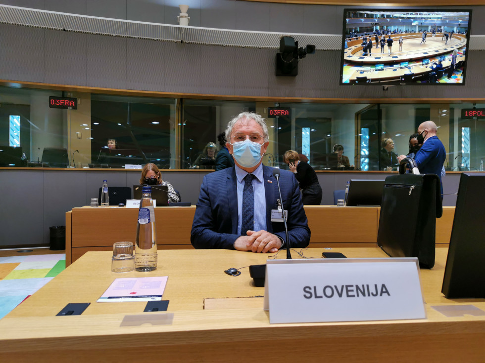 Minister Aleš Hojs na izrednem zasedanju Sveta za pravosodje in notranje zadeve v Bruslju, sedi za mizo, spredaj napis Slovenija