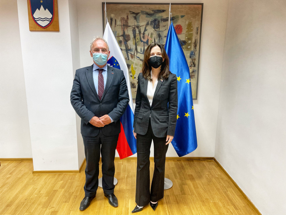 Minister za notranje zadeve Aleš Hojs in veleposlanica Združenih držav Amerike v Republiki Sloveniji Jamie Lindler Harpootlian, stojita pred zastavama v sejni sobi.