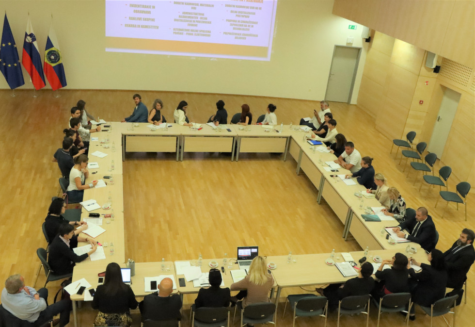 At the meeting, people sitting around a big table, watching the presentation on the wall