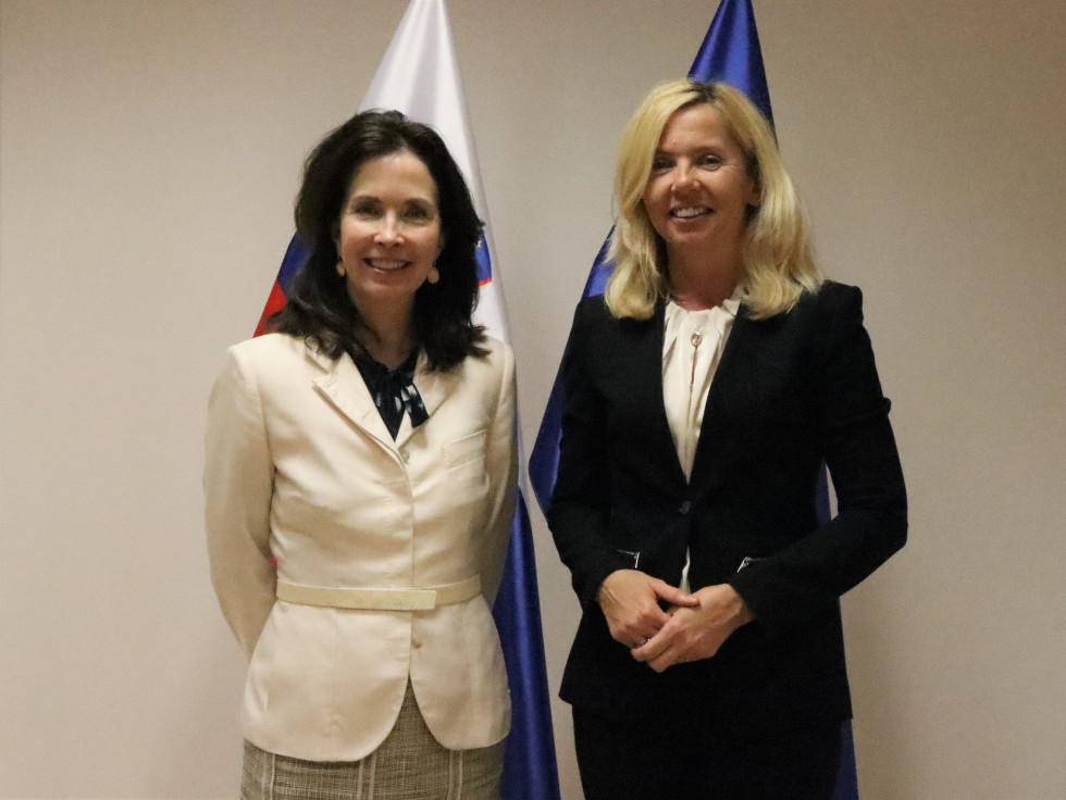 Ministrica za notranje zadeve mag. Tatjana Bobnar in veleposlanica Združenih države Amerike v Sloveniji Jamie Lindler Harpootlian stojita pred zastavami