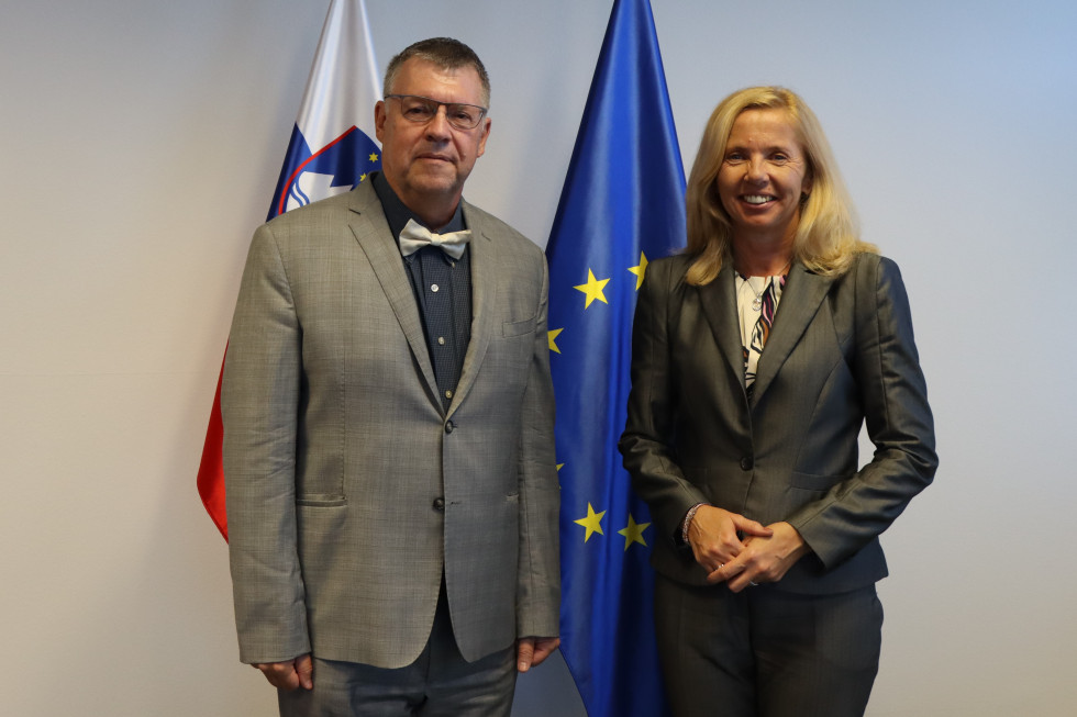 Ministrica Tatjana Bobnar in češki veleposlanik Juraj Chmiel stojita pred slovensko in evropsko zastavo