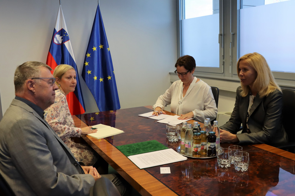 Sestanek ministrice Tatjane Bobnar in češkega veleposlanika Juraja Chmiela, sediat za mizo, ob njima njuni sodelavki, ob mizi slovenska in evropska zastava