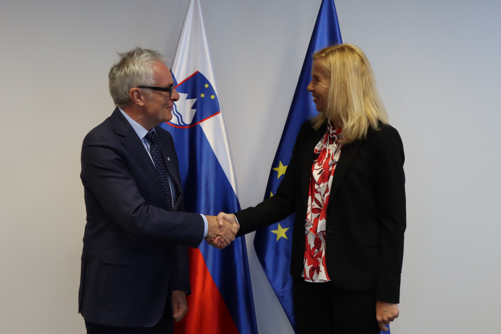 Rokovanje ministrice Tatjane Bobnar s predstavnikom UNHCR za Srednjo Evropo Rolandom Sebastianom Schillingom, za njima slovenska in evropska zastava