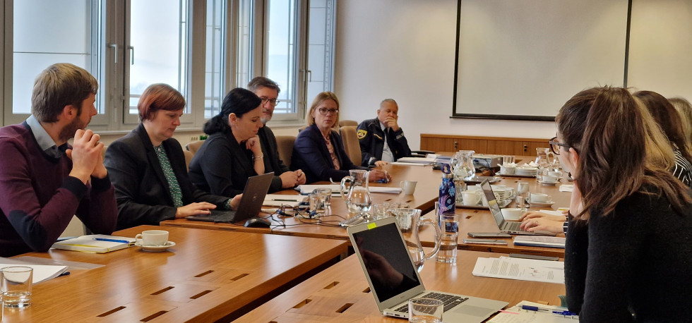 The participants sitting at the table and listening, the Minister is speaking